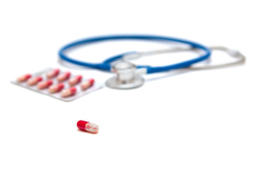 Blue stethoscope with red pills isolated