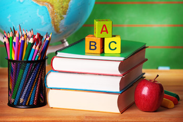 Stack of books, red apple, globe and pencils