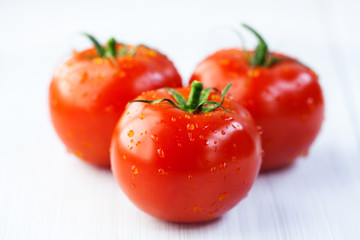 Three fresh tomatoes on wooden background