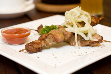 Restaurant food - meat on skewers and onion