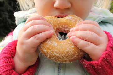 Child snacking on unhealthy sugary donut
