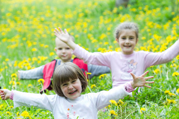 group of three children in dandelion meadow
