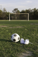 Футбольный мяч и детские белые кеды на футбольном поле
