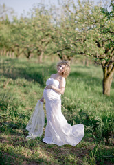 Fototapeta premium Beautiful pregnant woman in blooming garden