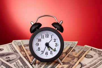 Alarm clock and dollars on red background