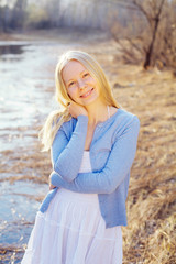 Fototapeta na wymiar Smiling blonde girl outdoor in forest near river