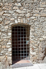 drzwi z pretow w starym kamiennym murze
