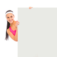 Smiling young girl looking out from blank billboard isolated
