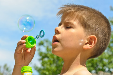 A little boy blows bubbles