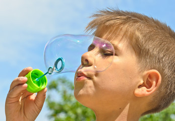 A little boy blows bubbles