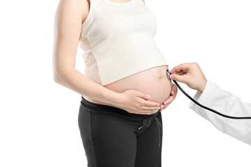 Pregnant woman being examined by a doctor with a stethoscope