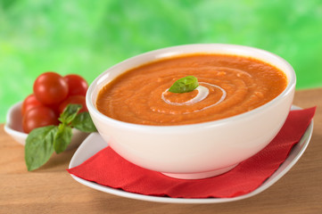 Cream of tomato with spiral of cream and a basil leaf