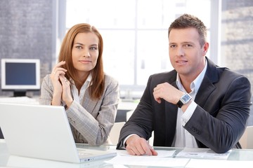 Young colleagues sitting at desk working