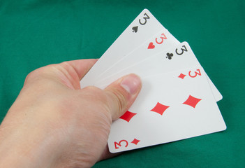 four threes in hand on card table