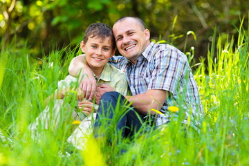 Fototapeta premium Father and son sitting in grass