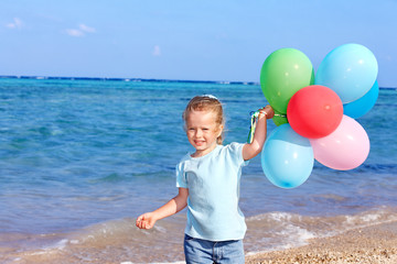 Child playing with balloons at the beach