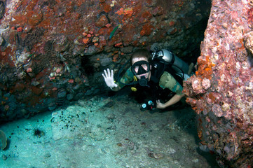 scuba diver swims through a small cave