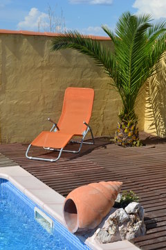 transat au bord de la piscine sous un palmier