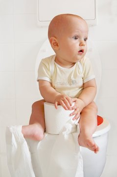 Cute baby sitting on a toilette