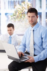 Obraz premium Handsome businessman sitting on top of desk