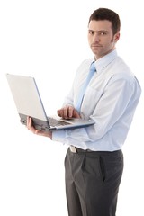 Casual office worker standing with laptop in hands