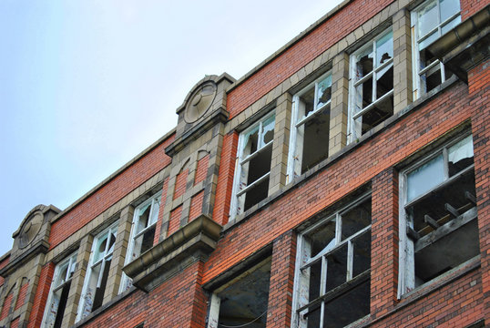 Derelict mill broken windows against a blue sky