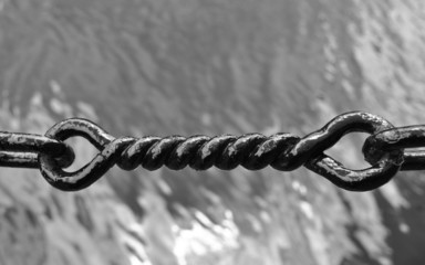 black twisted iron chain link with water in the background