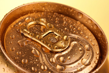 Golden metallic beer with water drops on yellow background