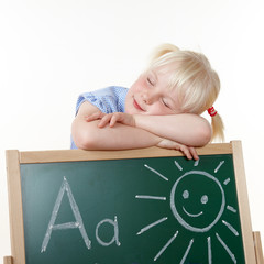 Cute blond girl with blackboard is tired of learning