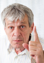 Angry senior man pointing his finger with rage at you