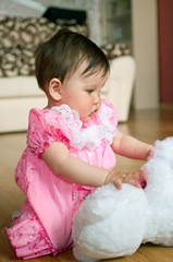 baby in pink dress with toy