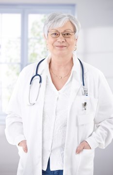 Senior female doctor smiling at hospital corridor