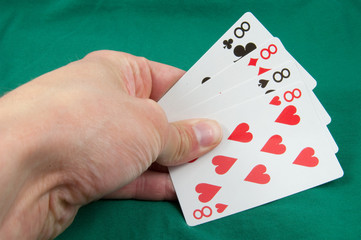 four eights in hand on card table background