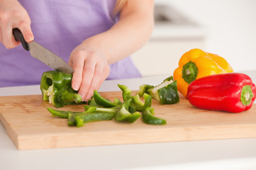 Woman cutting vegetables in modern kitchen interior