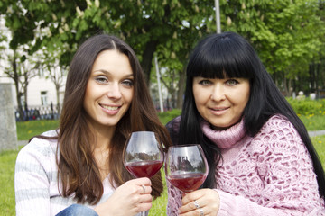 Mother and daughter drinking wine outdoors