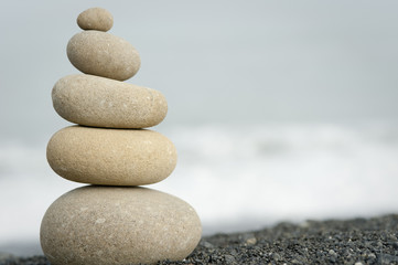 Fototapeta na wymiar pile of balanced rocks on black sand beach