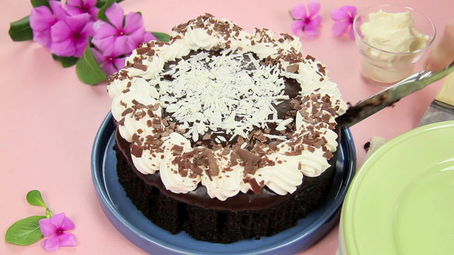 High shot of a chocolate mud cake being sliced with a knife.