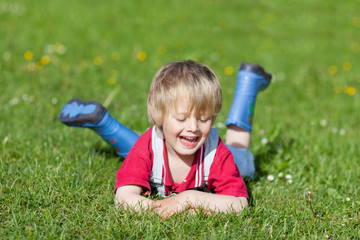 junge mit gummistiefeln auf der wiese