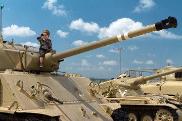 Cute boy saluting on the israeli tank. Museum of tanks. Israel.