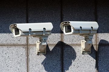 two white security cameras on the concrete wall