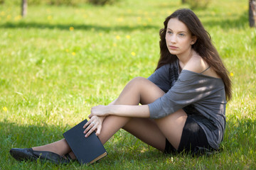 young student girl sitting in park with book