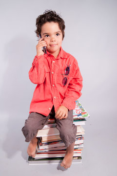enfant t&eacute;l&eacute;phonant sur une pile de livres