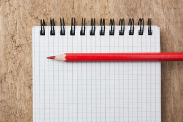 Notepad and pencil on the background of the wooden planks