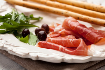 Serrano ham with olives, arugula and grissini