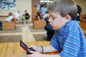 Boy Playing With a Small Computer Game