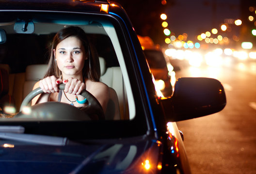 Young woman driving car in the night city
