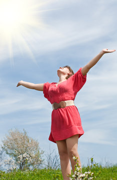 A young woman holds out her hands to the sun