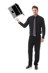 Young man balancing a laptop on his forefinger