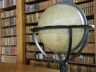 Rows of books on library shelves and a big globe