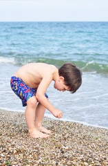 Boy gathering pebbles on the seashore